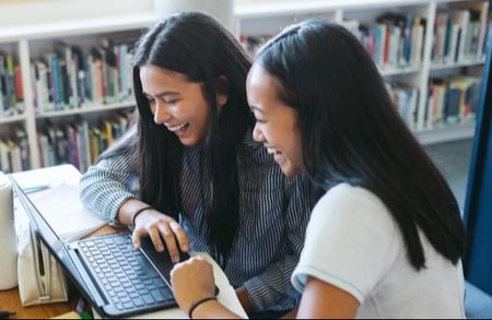 girls-library-laughing-laptop-inside-books-1